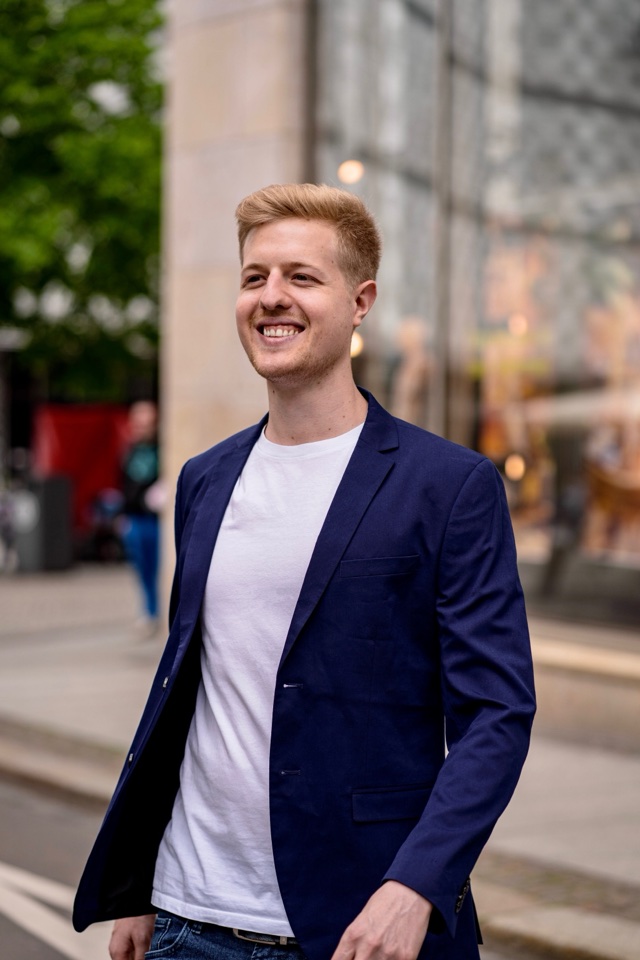 Nico Nice smiling in a navy blazer in the city
